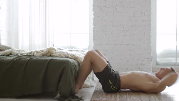 Athletic Man Is Doing Abs Exercises Crunches on Floor on Mat at Home Side View