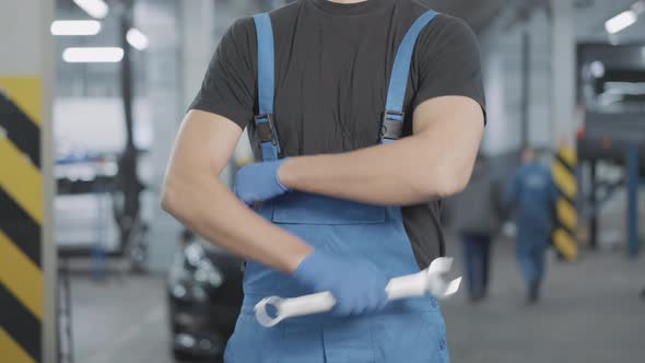 Unrecognizable Caucasian Auto Mechanic Standing in Car Workshop Crossing Hands