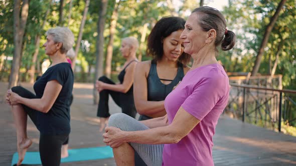 Young Black Positive Female Coach Correcting Senior Lady Yoga Beginner During Group Class Training