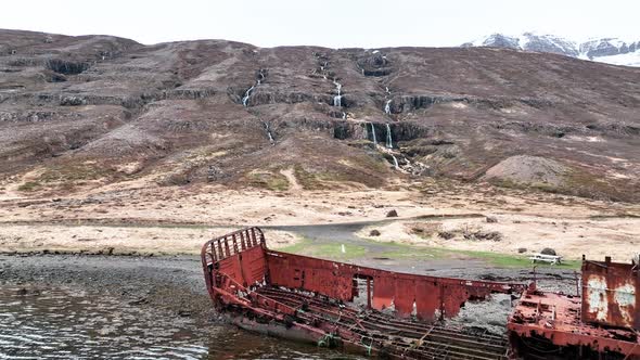 Ruins Of WWII US Navy LCM Ship In Mjoifjordur, East Iceland. Drone Pullback Shot