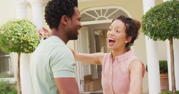 Happy biracial couple embracing with joy in front of new house