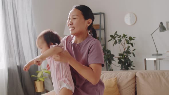 Joyous Asian Woman Playing with Baby Daughter at Home