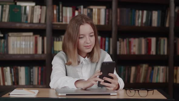 Girl in School Uniform Waving Hand Using Video Conference Call By Webcam on Smartphone Library in