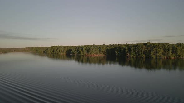 Aerial Birds Following View of a Hige River Bay and the Green Rainforest Under the Setting Sun