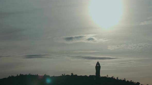 Wide shot of the sun over The National Wallace Monument near Stirling, Scotland