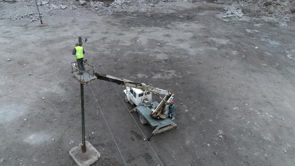 The electrician on the pole makes the wiring using an aerial platform.