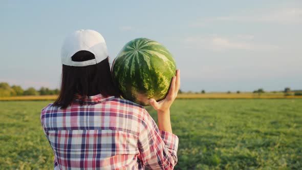 Farmer Carries a Ripe Watermelon on Her Shoulder