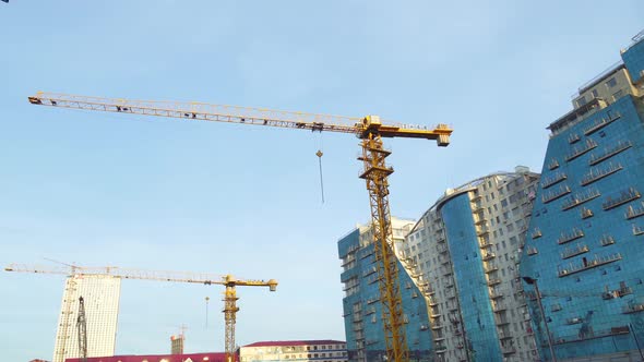 Construction site with cranes on the background of skyscrapers and blue sky.