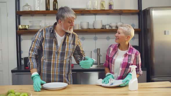 Portrait of Senior Couple Wiping Clean Dishes Together After Dinner