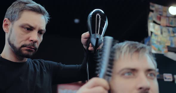 Brutal Male Barber Dries Hair and Combs Hair to the Client