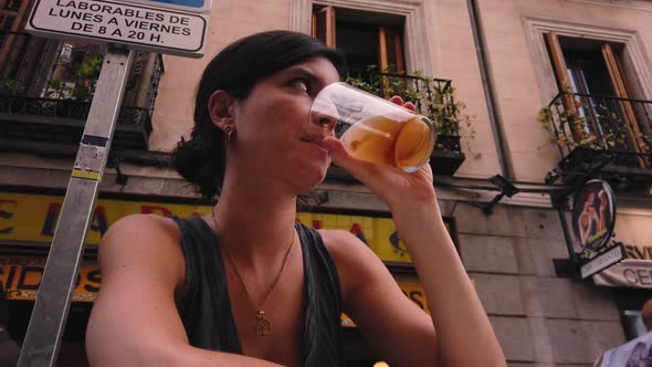 4k slow motion. Beautiful Caucasian woman drinks beer in a bar in Madrid (Spain). Spanish girl sitti