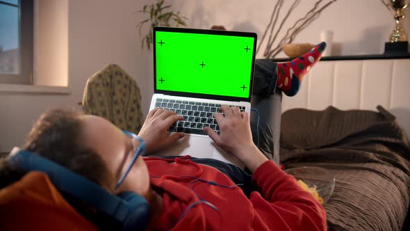 Young Man Lying on the Bed with Laptop - Green Screen