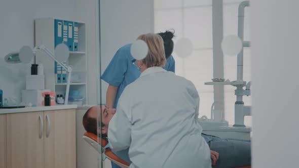 Medic and Nurse Examining Teeth After Oral Care Procedure