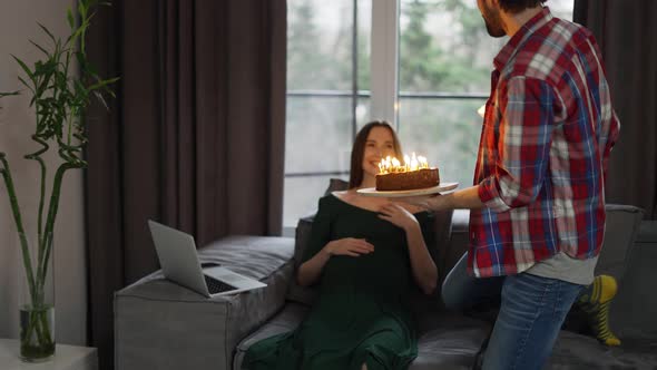 A Man with Birthday Cake and Candle Giving It to Pregnant Woman Celebrating Her Birthday