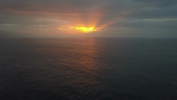 Slow Backward Flight Above Ocean Waves Towards Beautiful Colourful Sunset. Aerial Drone Shot of