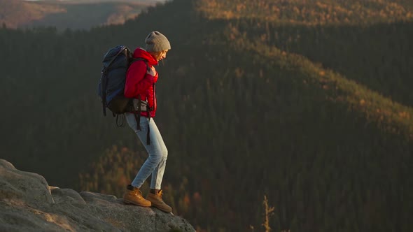 Slow Motion Young Adventurous Woman Hiker Backpacker in a Red Insulated Jacket and Jeans Hiking Down