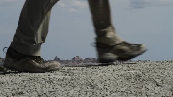 Hiker walks past camera - legs and boots visible - Badlands National Park, South Dakota