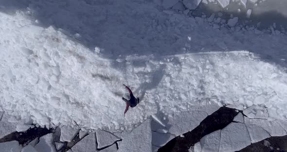 Aerial Dron View of Young Active Happy Man Walking on the Ice Glaciers Near Coastline of Winter Sea