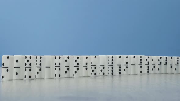 Domino Effect - a Series of Dominoes Falling Down the Chain on Blue Background