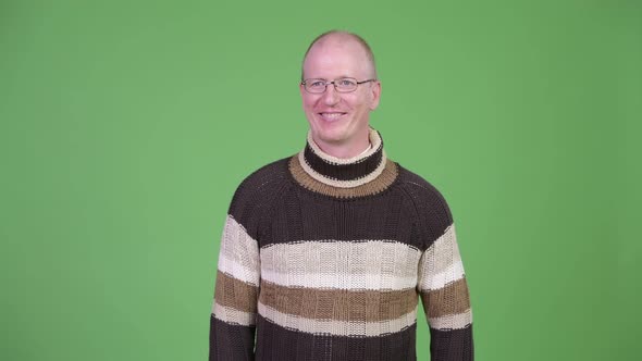 Happy Mature Bald Man Waving Hand and Wearing Turtleneck Sweater