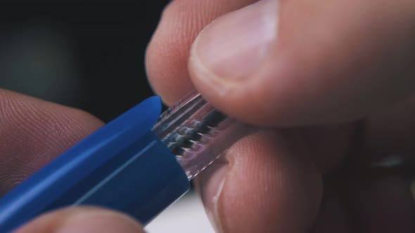 Person Takes Off Blue Cap From Ball Pen on Blurry Background