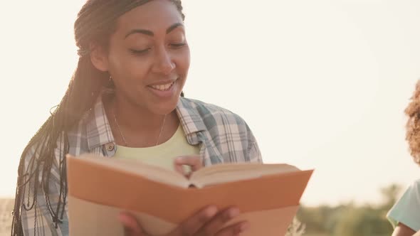 A beautiful afro-american mother is reading a book to her children