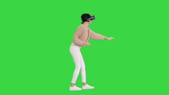 Cute Young Woman Walking and Using Interactive VR Headset on a Green Screen, Chroma Key.