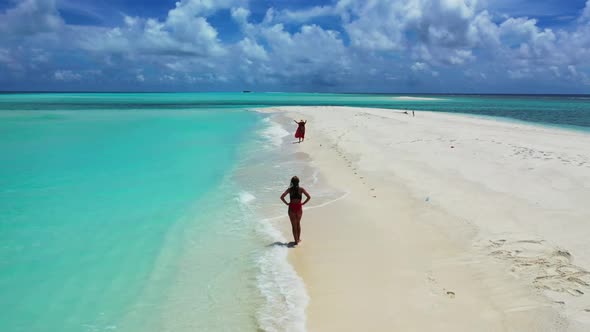 Female models enjoying life on beautiful coastline beach vacation by blue water and white sandy back