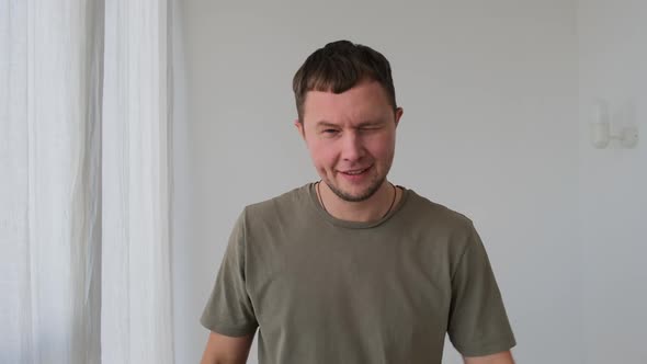 Playful Man in Tshirt Shows Tongue and Gestures in Room