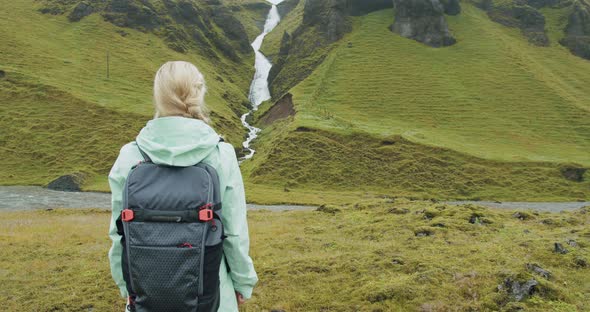 Woman Tourist with Backpack in Front of Icelandic Waterfall Near Fjadrargljufur at South Coast of