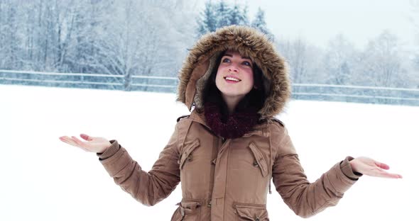 Smiling woman in fur jacket enjoying the snowfall
