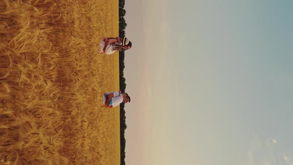 Vertical Screen Mom and Dad Carrying Children in Arms in Field