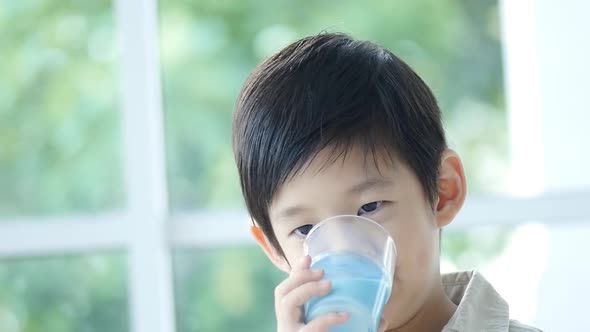 Cute Asian child drinking milk from a glass