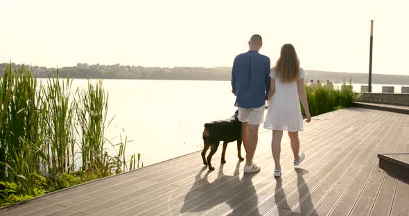 Young European Couple Going Near Lake with Dog