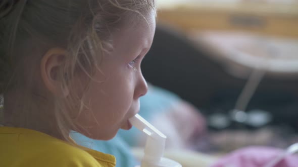 Pretty Small Girl Breathes with Inhaler Lying in Bed at Home