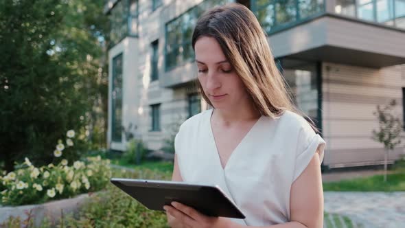 Young Business Woman Who Surfs the Internet on a Tablet Outdoors