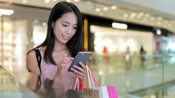 Woman use of mobile phone and holding shopping bags 