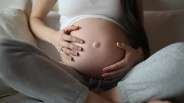 Close-up of the Pregnant Woman's Belly While She's Stroking and Touching It with Her Hand