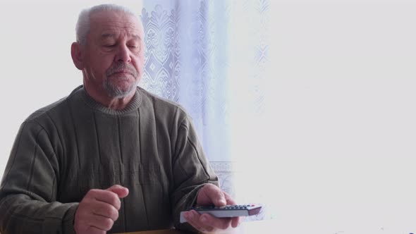 An Old Man Switches TV Channels with a Remote Control