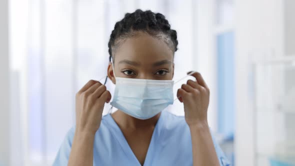 Close Up View of Mixed Race Female Nurse Rasing Head and Taking Off Medical Protective Mask While