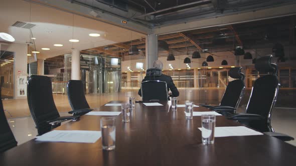 Mature Businessman Riding Office Chair in Boardroom