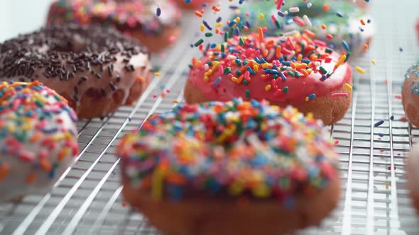 Sprinkling candy chocolate on frosted doughnut. Slow Motion.