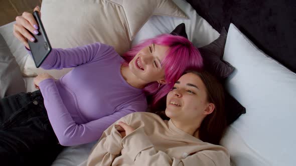 Carefree Woman and Female Friend with Birth Anomaly Making Selfie in Bed