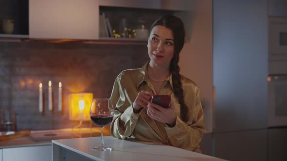 Woman Texting on Smartphone and Drinking Wine at Home