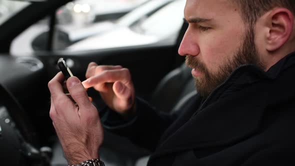 young bearded businessman  using smart phone driving car