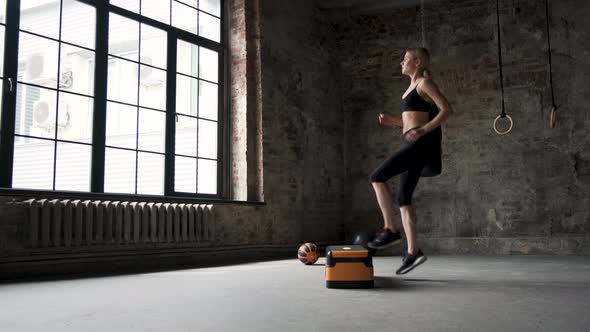 woman jumping on step platform slow motion. female legs sneakers active workout in gym