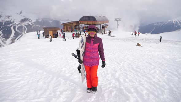 Girl Snowboarder with Snowboard on Mountain Top on Ski Resort. Winter Sports and Winter Vacation alt