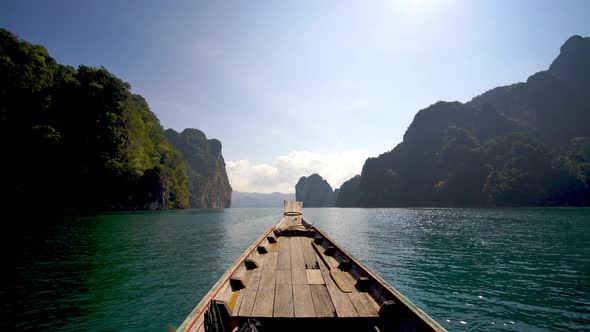 Travel lake landscape on wooden longtail boat on a tropical limestone cliff exploring Khao Sok Lake