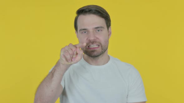 Angry Young Man Arguing on Yellow Background