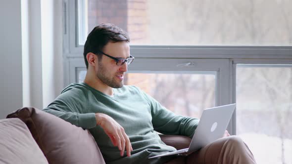 Young attractive man holding video conference remotely from home office